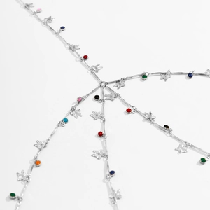 Macro detail of multilayer silver body chain with star charms and colorful beads