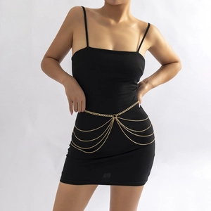 Détail d'une chaîne de taille dorée multicouche avec franges et anneau central en métal