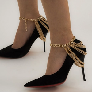 Detailed view of black pointed heels with multi-layer gold chain fringe and red soles
