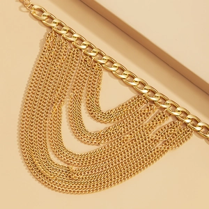 Close-up of golden multi-layer anklet with thick Cuban chain and cascading draped tiers