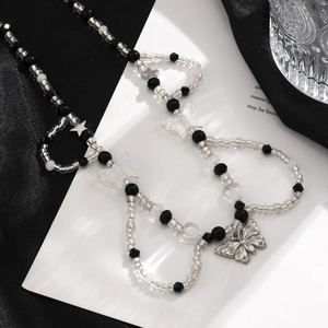 Detalle de collar de cuentas con colgante de mariposa plateada y estrellas en seda negra