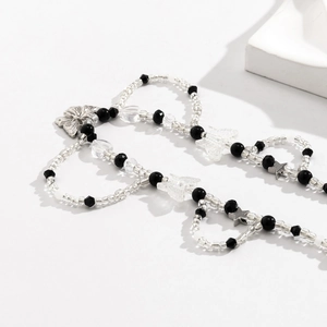 Detalle de dijes de mariposa y estrella Y2K en un collar de cuentas blanco y negro
