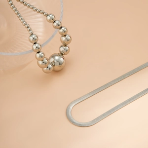 Detail van de zilverkleurige slangenketting en ketting met gegradueerde metalen kralen