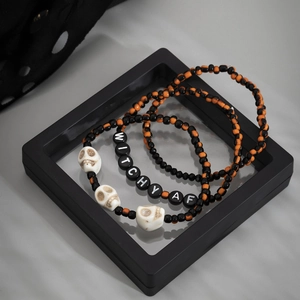 Detalle del set de tres pulseras góticas con calaveras y letras de Witchy AF decorativas