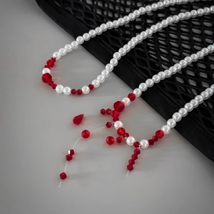 Detail of gothic pearl choker with red crystal droplets on a mesh background texture