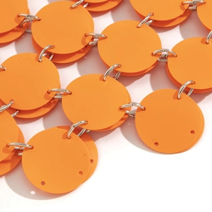 Makroaufnahme von orangefarbenen Pailletten und Silberringen eines Körperketten-Rocks