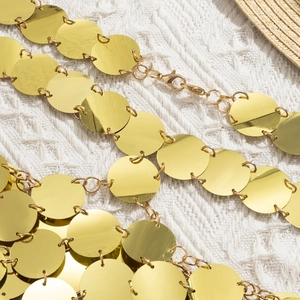 Détail de la chaîne de corps à paillettes dorées sur un fond en tricot de plage