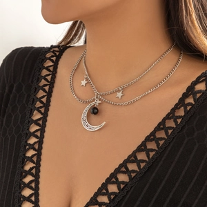 Dettaglio della collana argentata con luna e stella e perla nera su pizzo con scollo a V