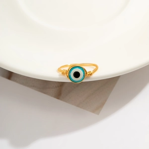 Macro shot of handmade gold wire-wrapped ring with blue evil eye bead detail