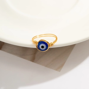 Macro view of handmade gold wire-wrapped ring with a blue evil eye bead detail