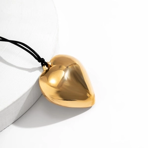 Detailed view of a polished gold heart pendant on a black adjustable cord necklace