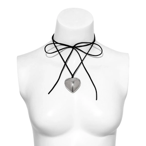 Close-up of a large silver heart pendant on a black velvet choker with bow tie knot