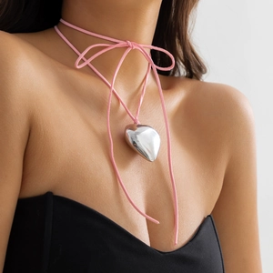 Detail of 3D metallic heart pendant with pink suede cord choker tied in a bow