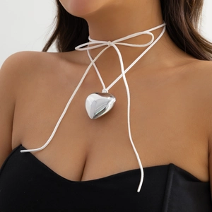 Close-up of a silver heart pendant necklace with adjustable white ribbon on a model neck