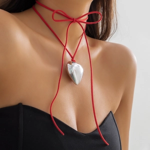 Close-up of a large polished silver heart pendant on a red velvet tie choker necklace