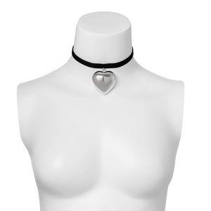 Detail of a velvet choker with a silver heart pendant displayed on a white mannequin