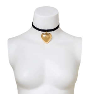 Detail of a large gold heart pendant on a black velvet choker shown on a white mannequin