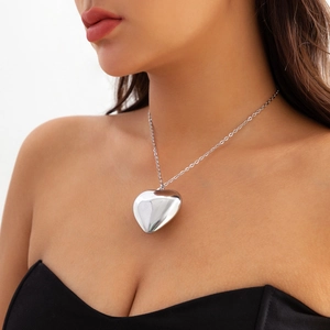 Detailed close-up of a silver oversized heart pendant necklace worn on a velvet chain