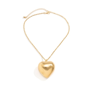 Macro view of a polished gold puffed heart pendant with a metallic chain and lobster clasp