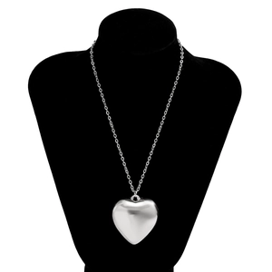 Macro shot of a polished large silver heart pendant on a stylish long metal chain