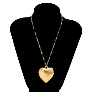 Polished gold heart pendant necklace displayed on a black velvet mannequin