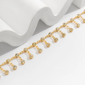 Détail d'une chaîne de taille bikini dorée avec glands en strass brillants et maillons