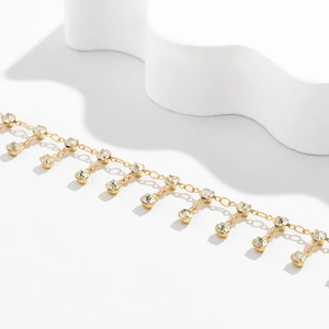 Détail macro de la chaîne de taille géométrique dorée avec pampilles en strass