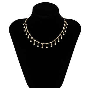 Détail d'une chaîne de corps dorée à franges ornée de strass en cristal sur un support noir
