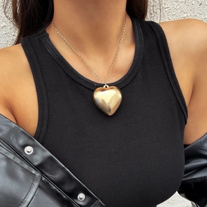 Polished gold heart pendant necklace with velvet chain tassel on a female model