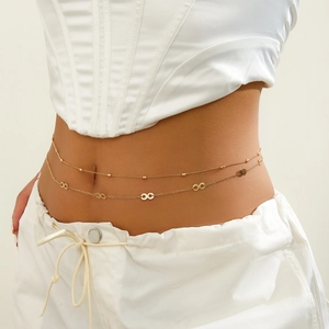 Close-up of double-layer gold waist chain with infinity symbols on a white lace top