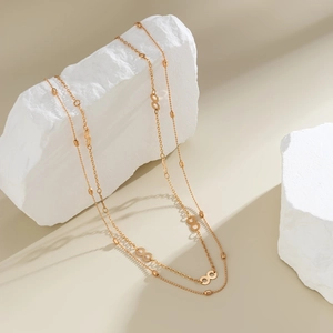 Detail of layered gold chain body jewelry with infinity link charms on stone