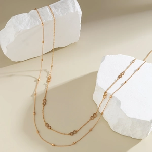 Detail of golden double layer waist chain featuring infinity symbols and beads