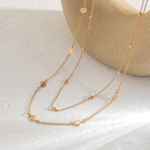 Detail of double-layer gold chain body jewelry featuring hollow smiley face charms