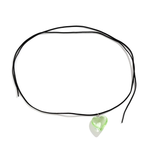 Detailopname van een groene glazen hartvormige hanger met zwart koord voor dames