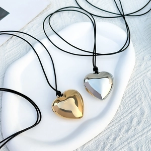 Detail van gepolijste hartvormige hangers in goud en zilver met zwart koord