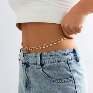 Détail d'une chaîne de corps dorée double couche avec strass en cristal sur la taille