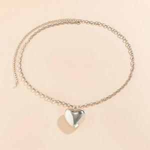 Detailopname van een zilveren hartvormige hanger aan een schakelketting tailleketting
