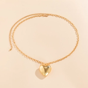 Macroshot van de 3D gouden hartvormige hanger met spiegelglans en dikke metalen schakels