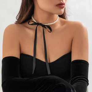 Detail van een vintage parelchoker met een lange zwarte satijnen strik op een model
