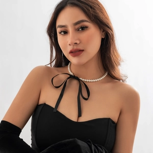 Detailopname van een parelketting met zwarte fluwelen strik op een model in vintage stijl