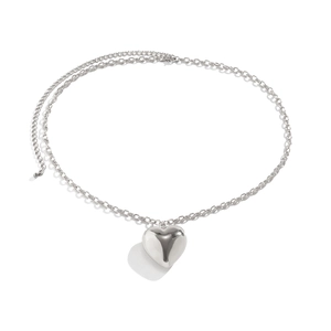 Macro-opname van de gepolijste zilveren hartvormige hanger aan een fijne metalen ketting