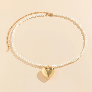 Detail van een gouden hart hanger en parelketting met een handige karabijnsluiting
