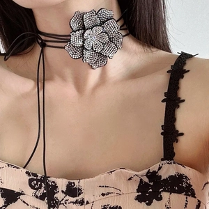 Detail van camelia choker met fonkelende kristallen en gelaagde zwarte koorden