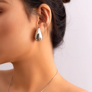 Close-up of polished silver teardrop earrings with a high-gloss finish on a female model
