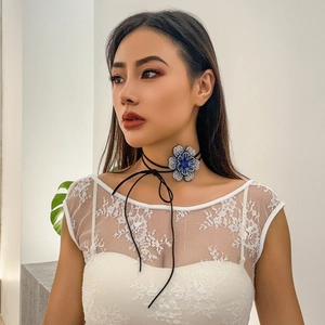 Detail van blauwe strass bloem choker met zwarte waskoorden en lange kwastjes