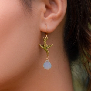 Vintage gold swallow drop earrings with pear-shaped opal stone shown on a model