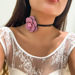 Detail van roze camellia choker met kristallen pavé op een zwart koord halsketting