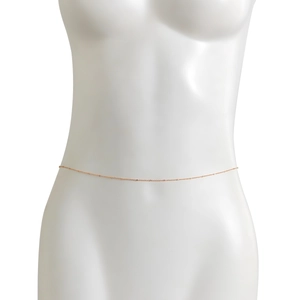 Detail of rose gold waist chain with fine metal links and delicate beads on a model