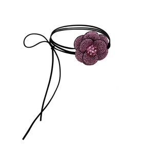 Detailopname van camelia bloem choker met roze strass steentjes op zwart waxkoord