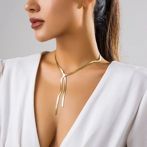 Close-up of a gold snake chain necklace with a chic bow tassel detail on a model